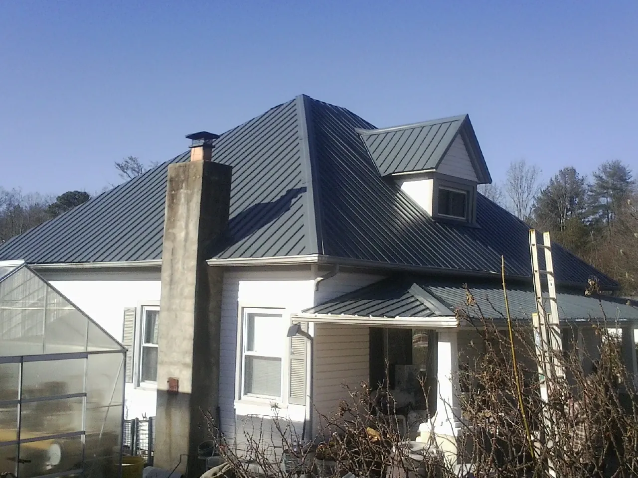 Dark blue standing seam metal roof on a white farmhouse with dormer — Slate & Tile Roof Repair by Roofing Brothers in Mahopac