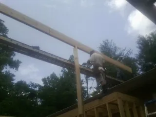 Carpenter setting a ridge beam over a new addition frame — Ice Dam Removal by Roofing Brothers in Mahopac