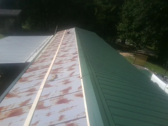 Old rusted panels beside newly installed green metal roofing — Wind Damage Roof Repair by Roofing Brothers in Mahopac