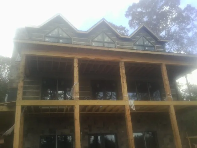 Dormers and porch framing on a large log home under construction — Roof Coating work by our crew in Mahopac