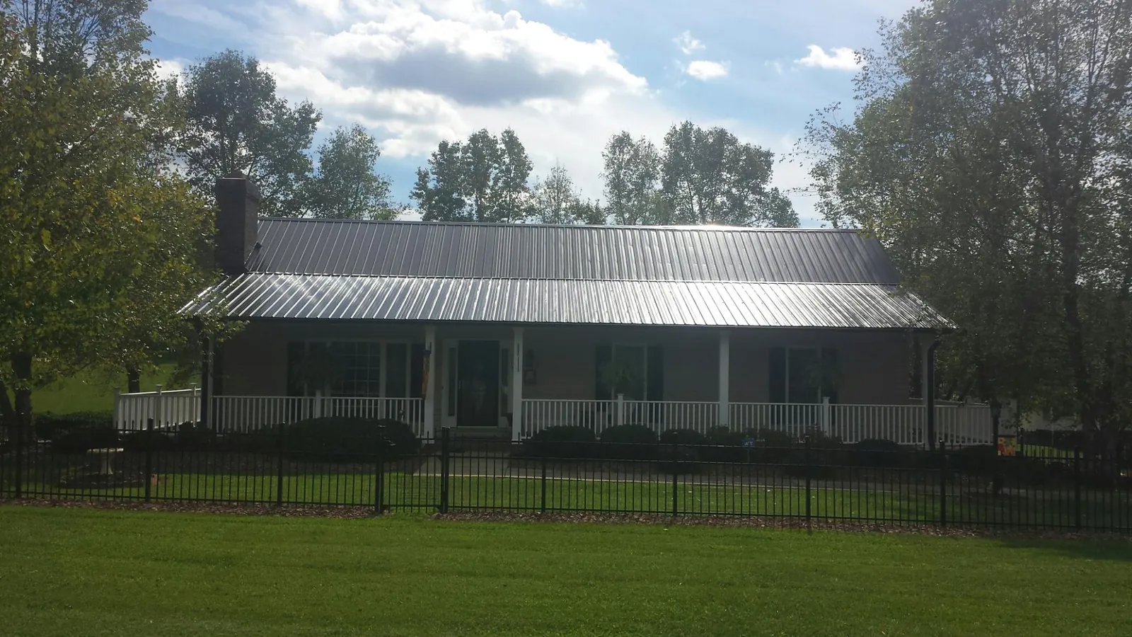 Gray metal roof on a brick ranch with a full width front porch — Gutter Guard Installation work by our crew in Mahopac