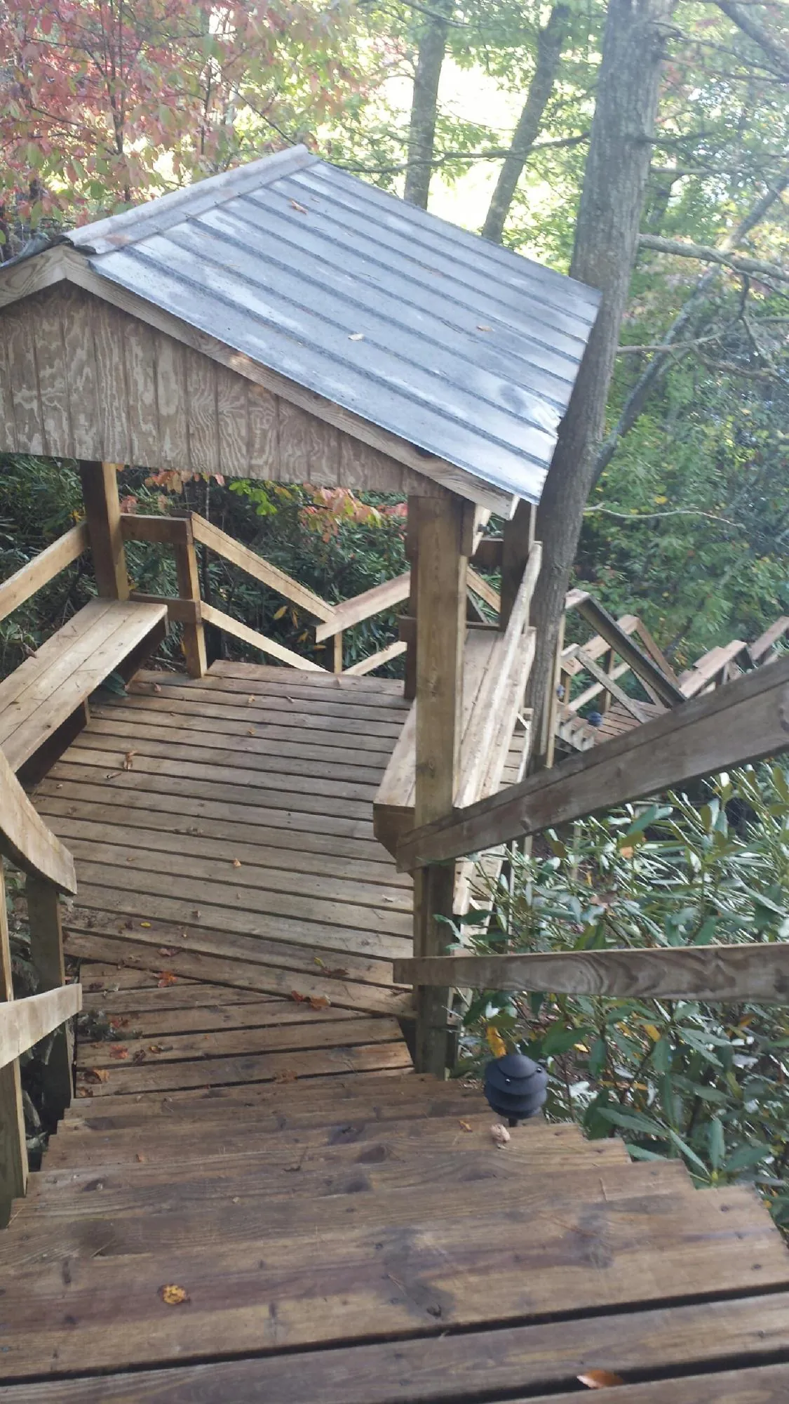 Metal roofed shelter over wooden steps on a wooded walkway — Skylight Repair & Installation work by our crew in Mahopac
