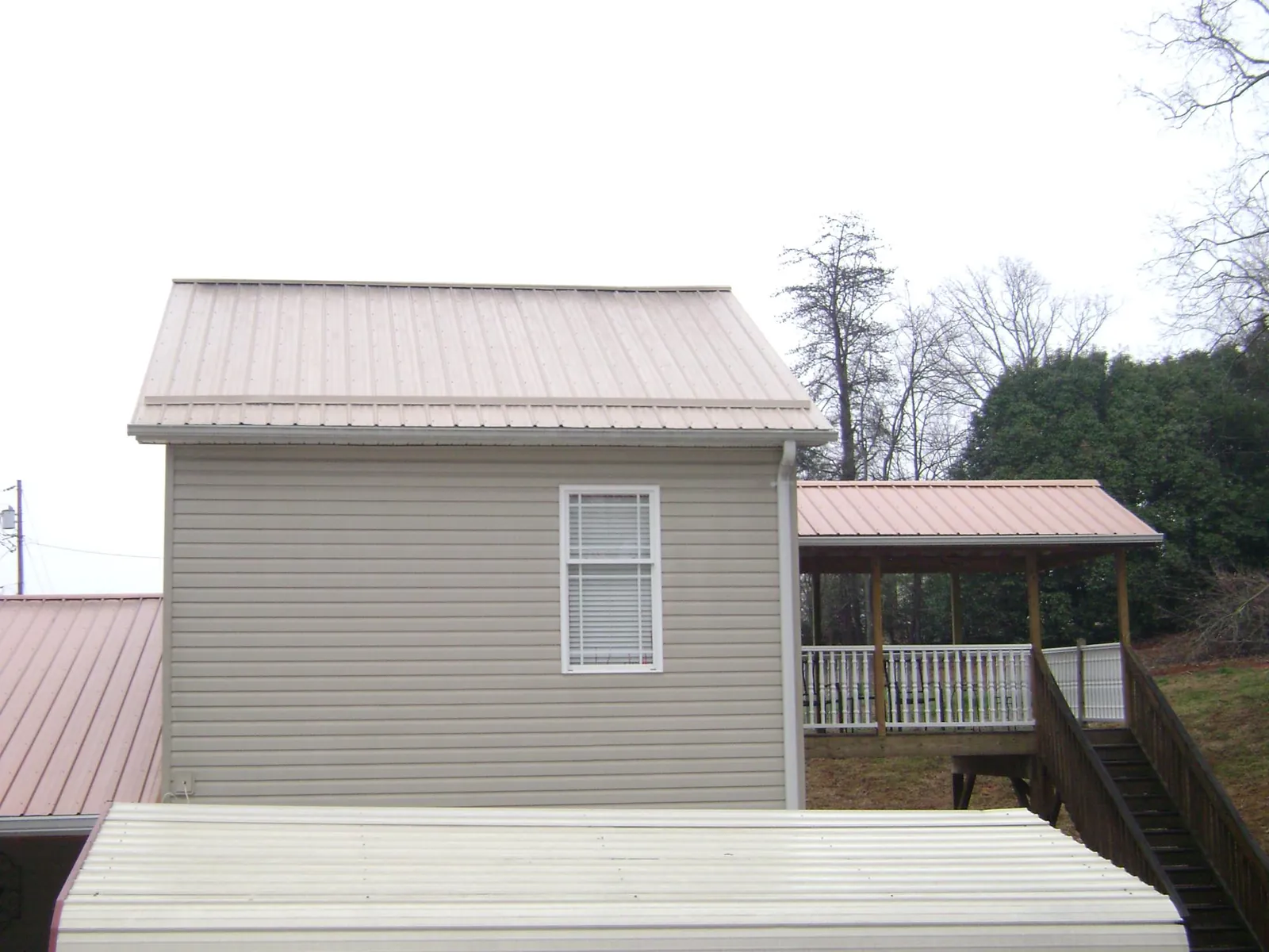 Tan metal roofs on a two story addition and attached porch, from a Roof Replacement job in Mahopac