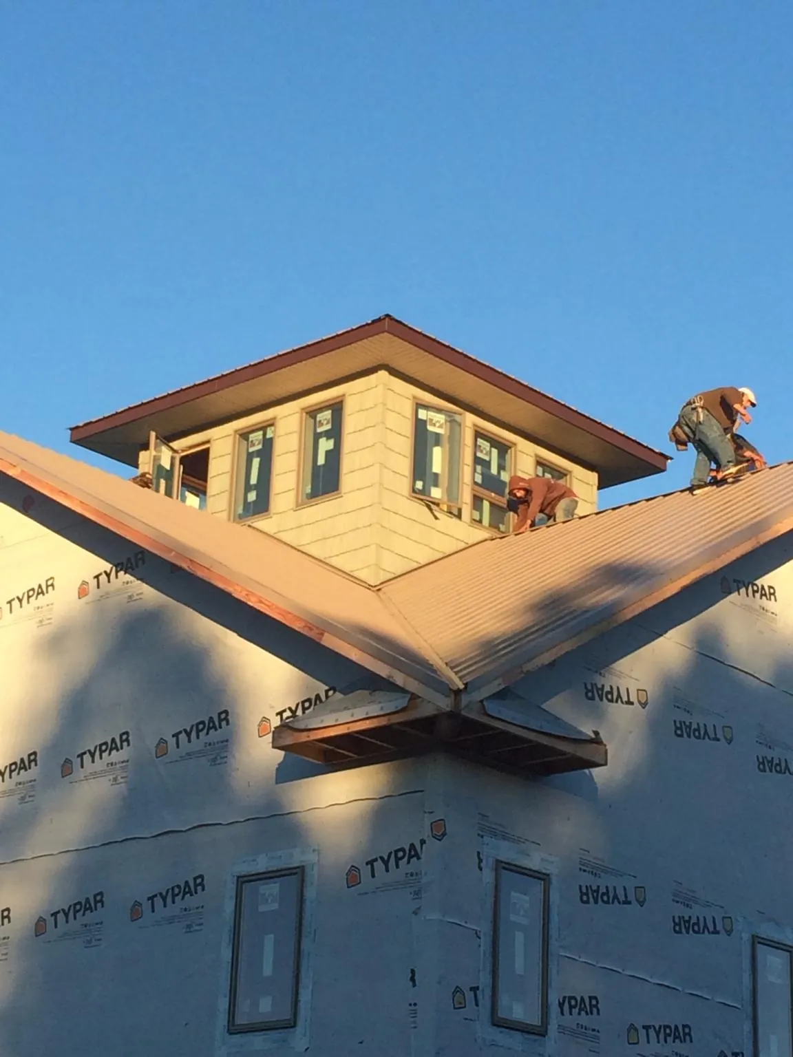 Roofers working around a rooftop cupola on a new metal roof at sunset — Roof Waterproofing in Mahopac by Roofing Brothers